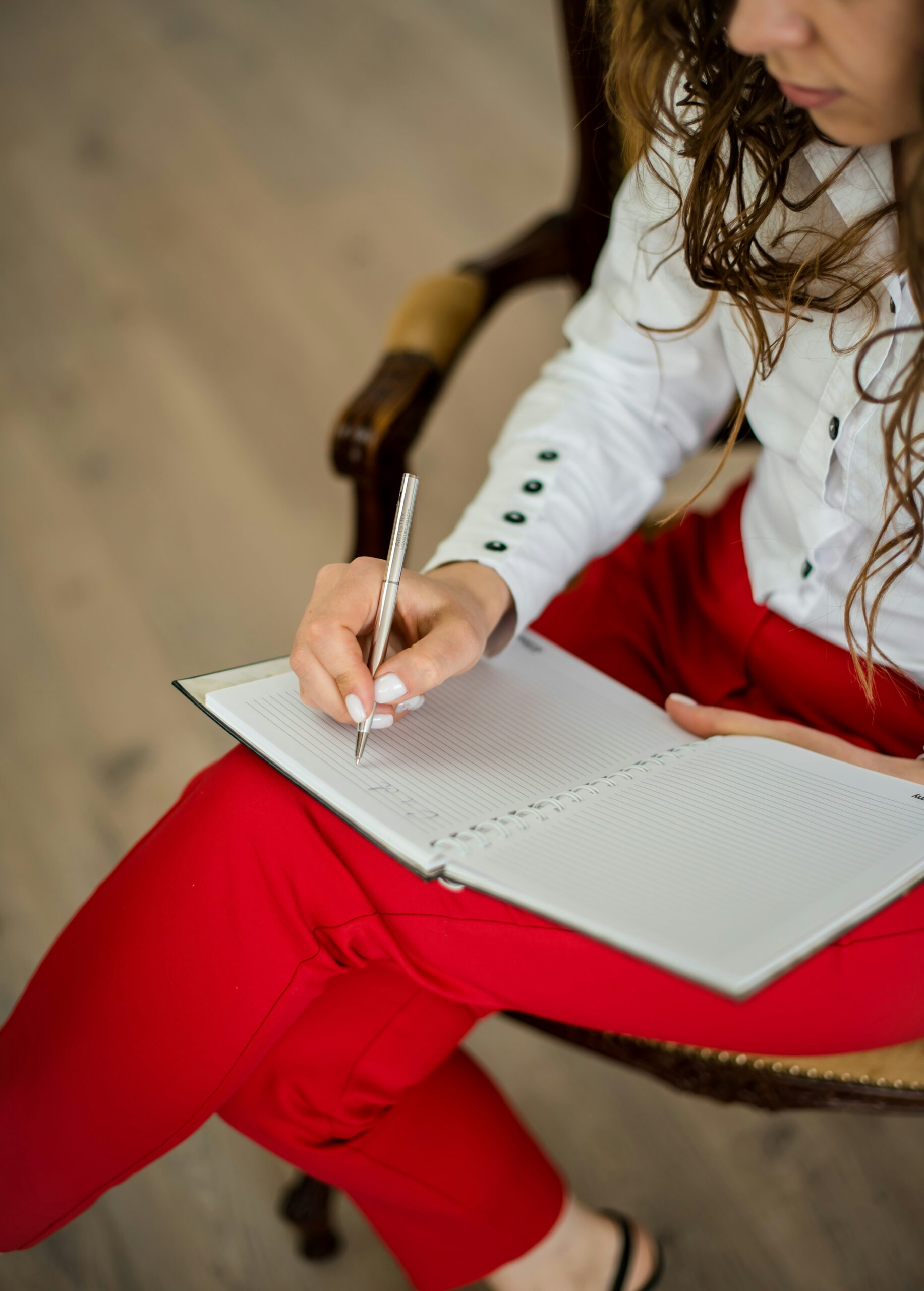therapist sitting in chair looking down writing notes in a notebook